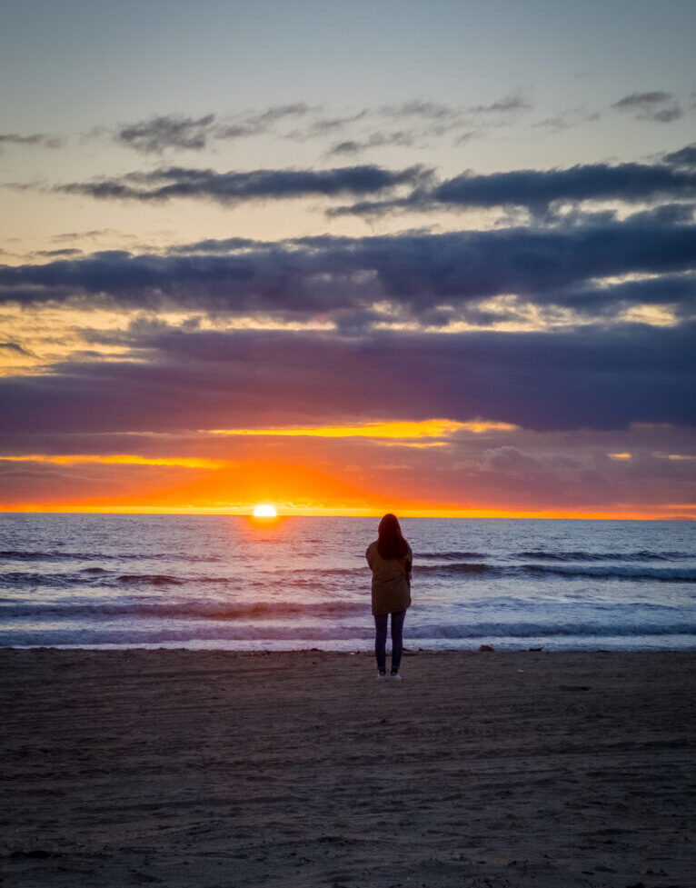 silhouette of woman standing with beach sunset