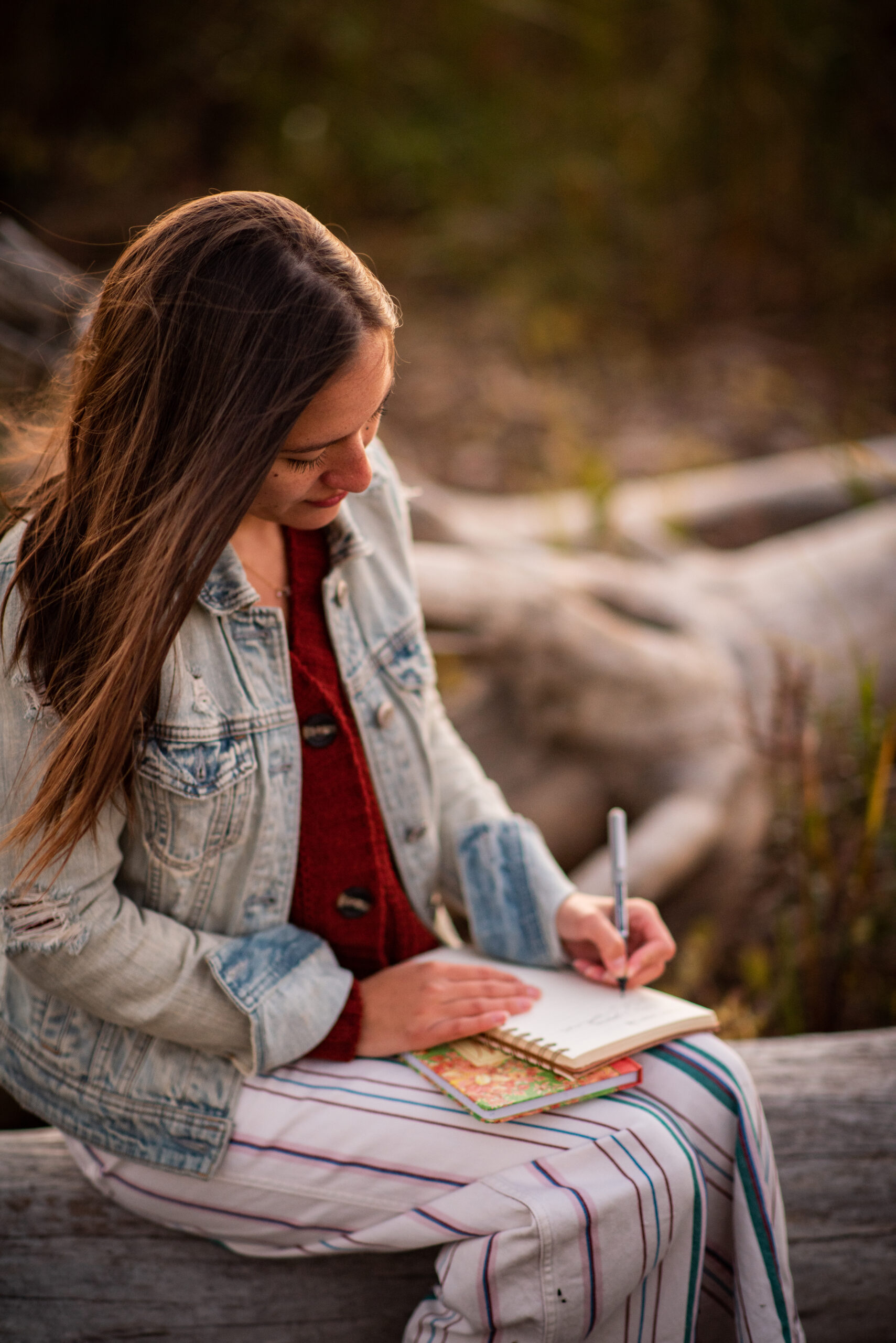 woman sitting on a log writing in a journal