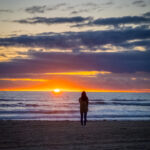 sillouhette of woman standing with beach sunset