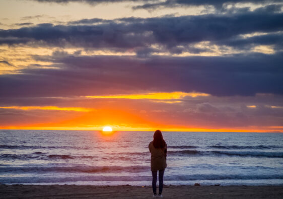 sillouhette of woman standing with beach sunset