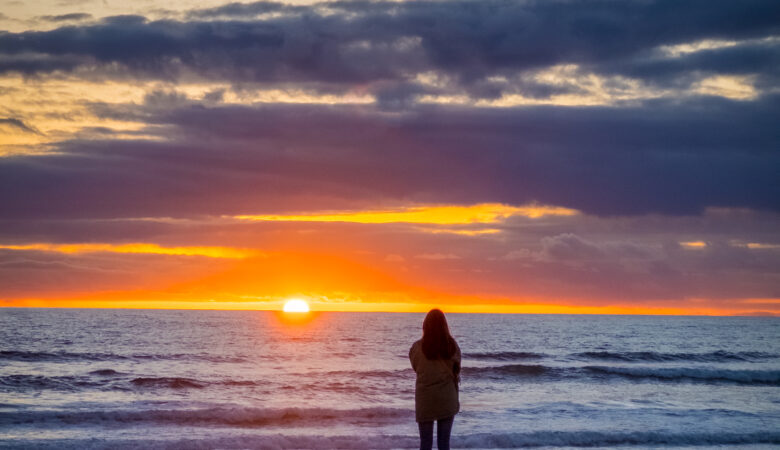 sillouhette of woman standing with beach sunset