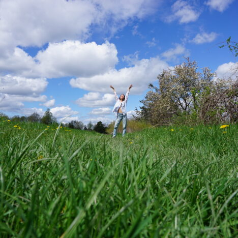 Woman in field raising arms