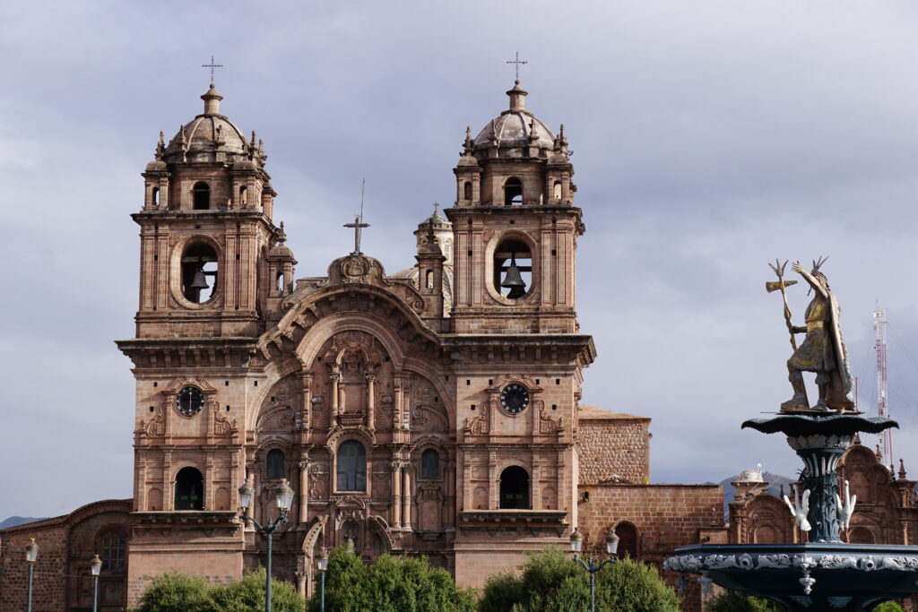 Catholic church front and top of water fountain with Inca statue on top