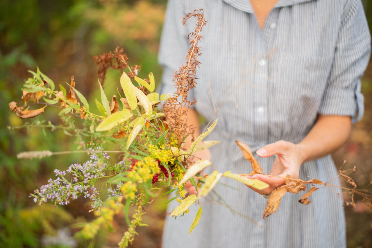 Woman in striped dress with a grouping of foraged flowers in her hands