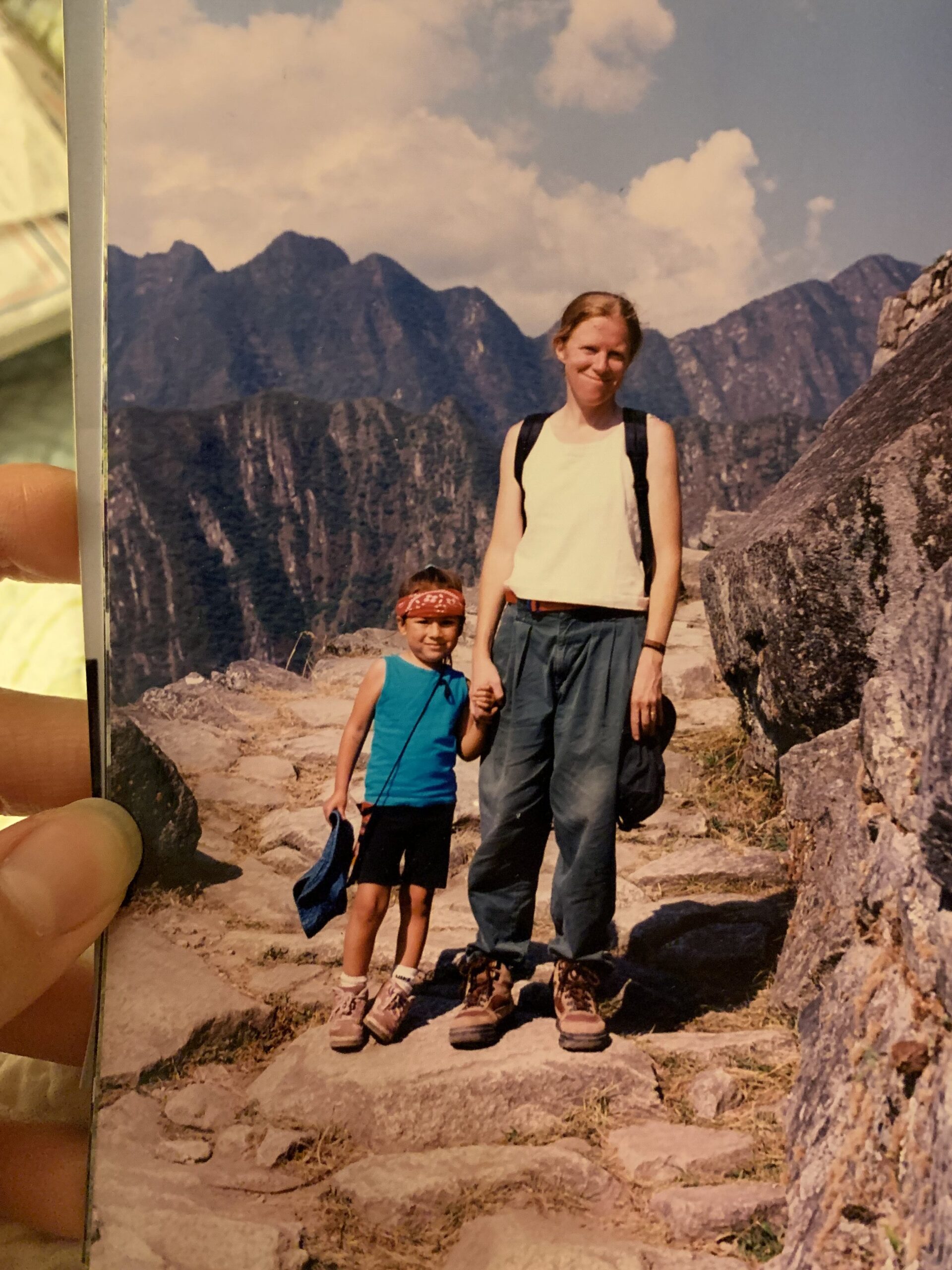 4 year old girl holding hands with mom on stone path with mountains in background.