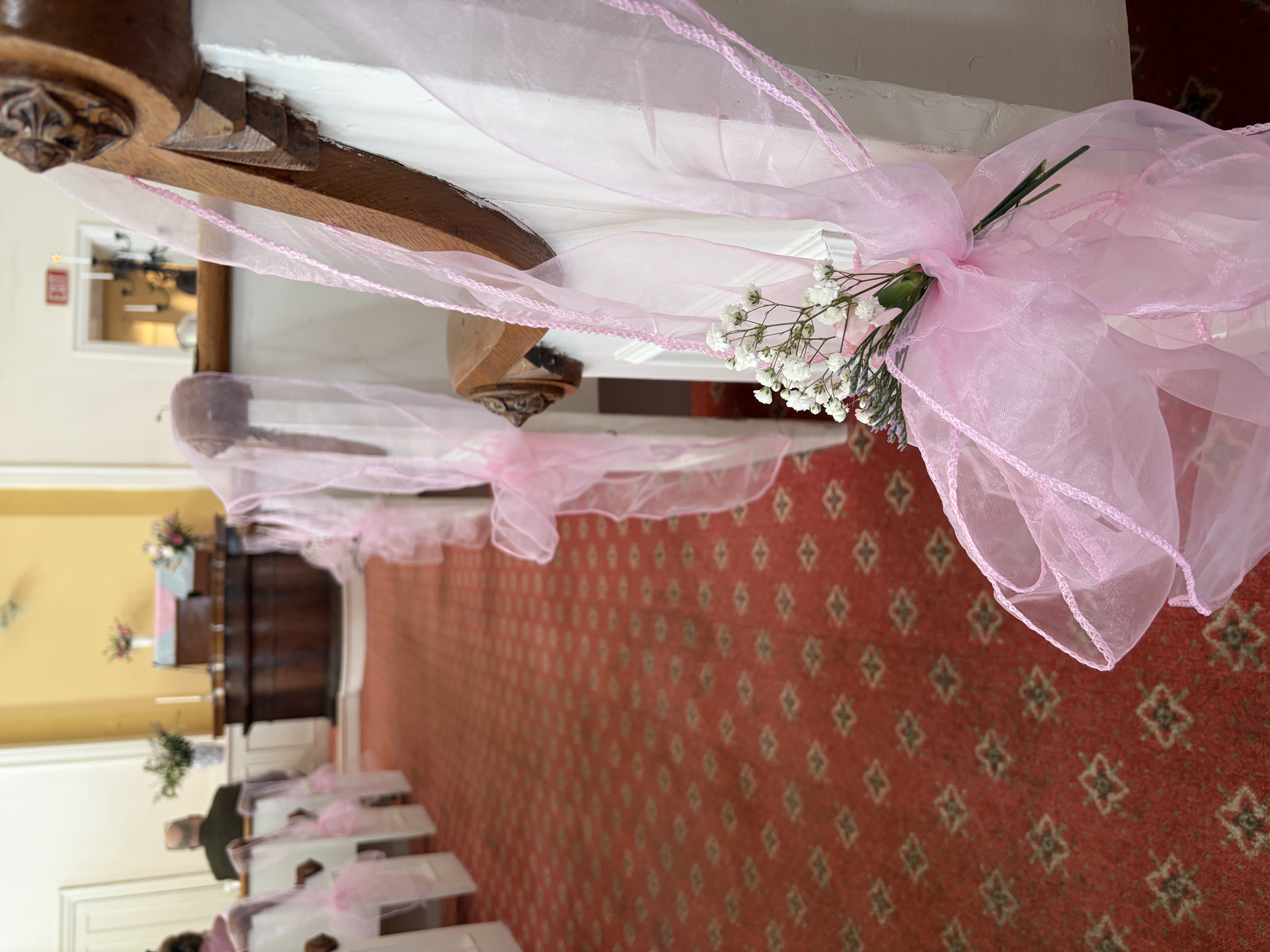 Church aisle floral design with pink sheer hanging bows and babys breath accent.